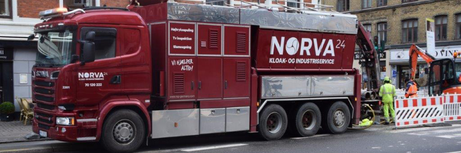 Norva24-lastbil udfører kloak- og industriservice nær afspærringer og byggeudstyr i byområdet