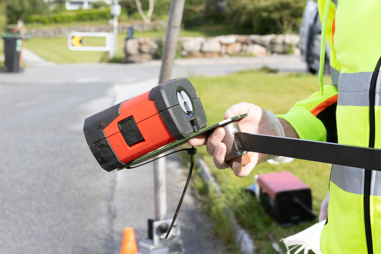 Arbeider holder rød kabelsporer mot svart kabel under inspeksjonsarbeid