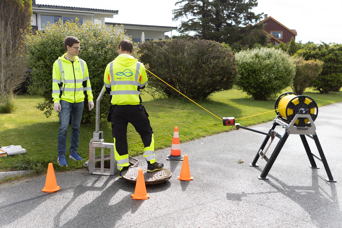 Tekniker i refleksvest ved avløpsinspeksjon med kamera og utstyr på gate