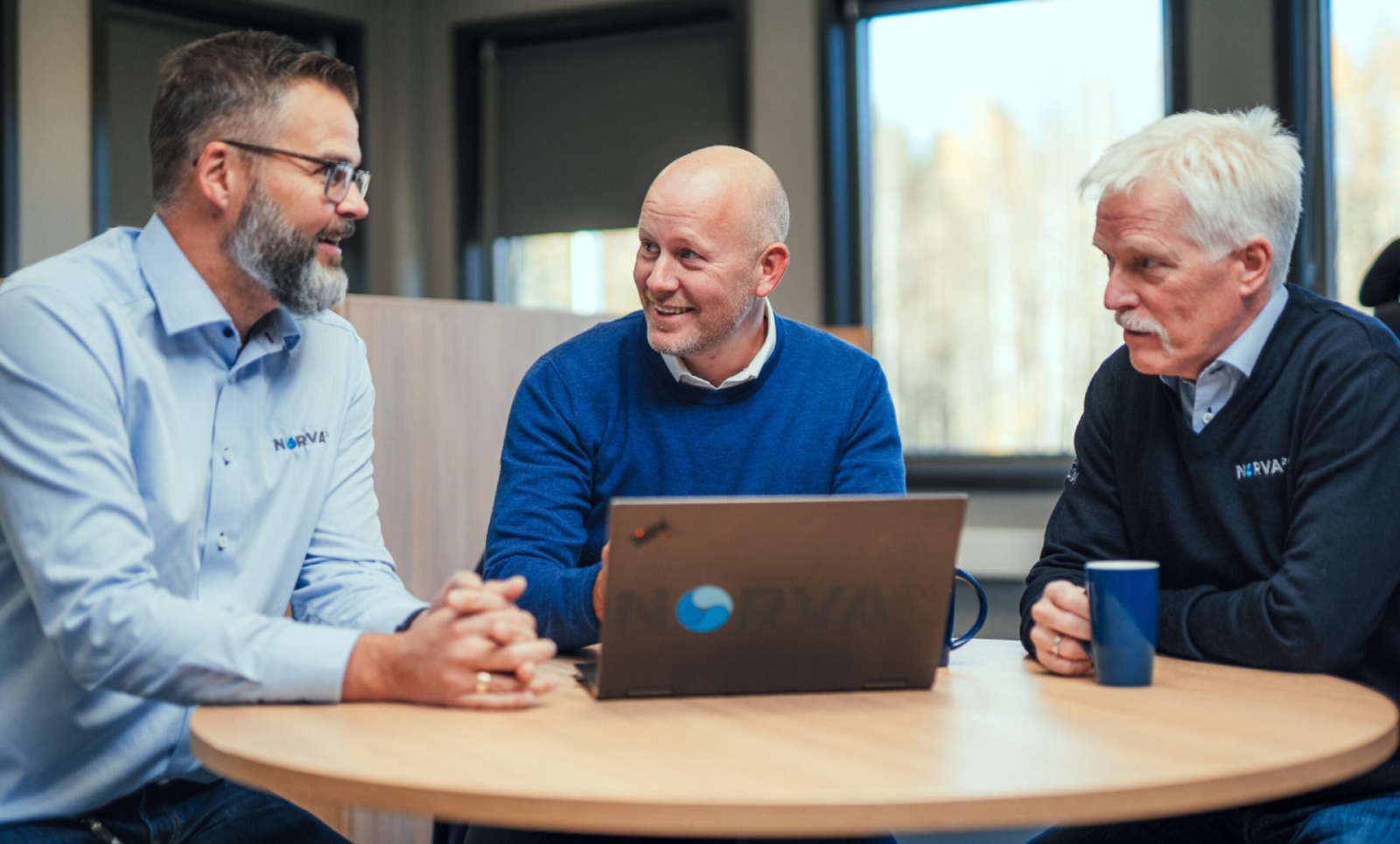Drei Norva24-Kollegen in freundlicher Diskussion am Bürotisch