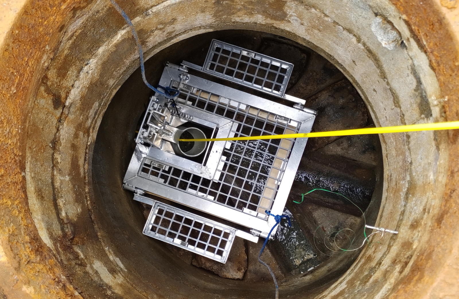Inspeksjonskamera med gule og grønne kabler senket ned i avløpskum