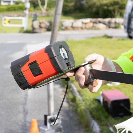 Arbeider holder rød kabelsporer mot svart kabel under inspeksjonsarbeid