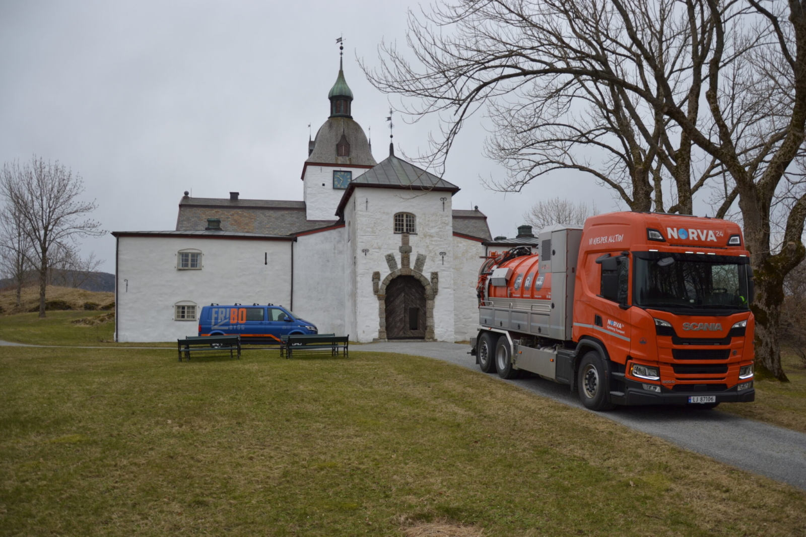 Oransje Norva24-lastebil parkert utenfor en historisk hvit norsk kirke