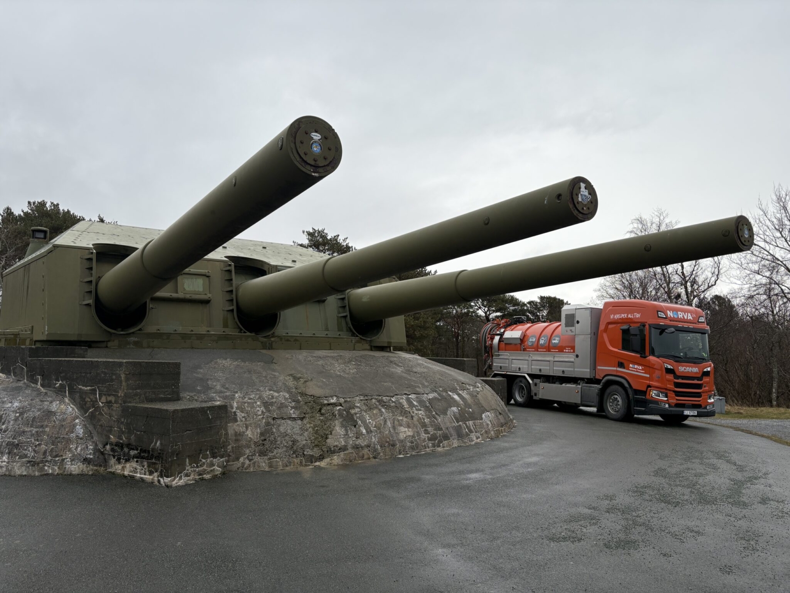 Oransje Norva24-lastebil ved stort kystartilleribatteri