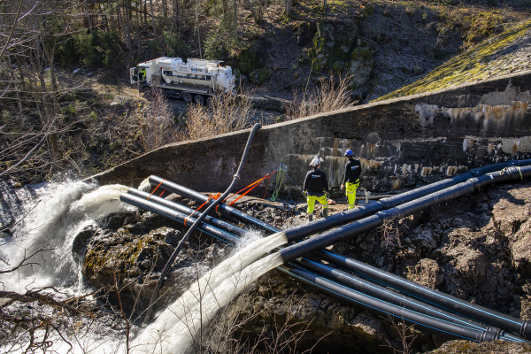 Arbetare rengör och underhåller ett vattensystem i ett öppet område.