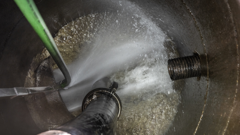 High-pressure flushing inside a tank to remove contaminants.