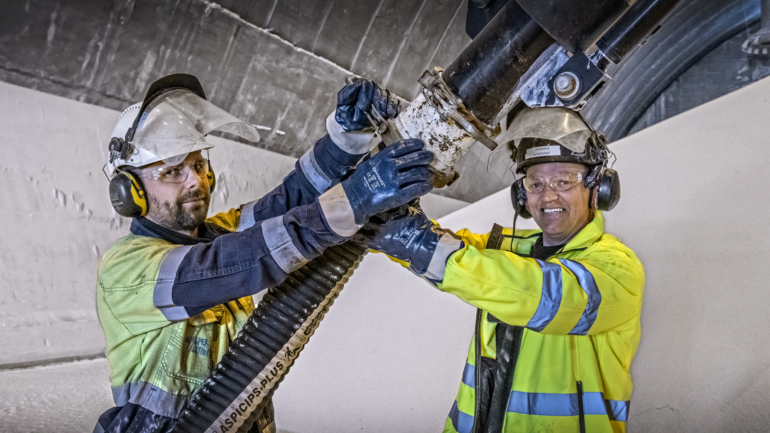 Operators working together to connect industrial equipment.
