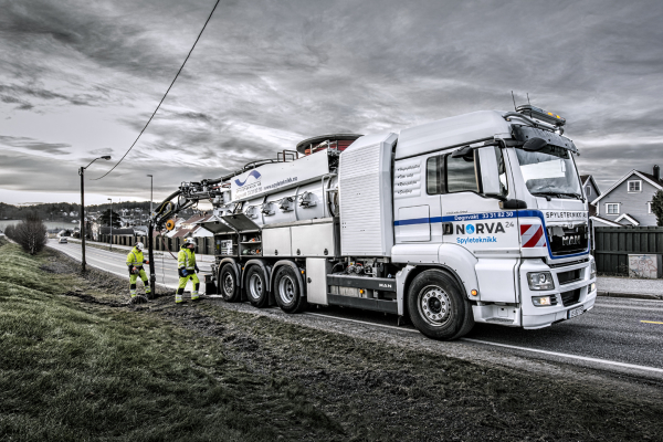 A vacuum truck empties a sand trap along a rural road.