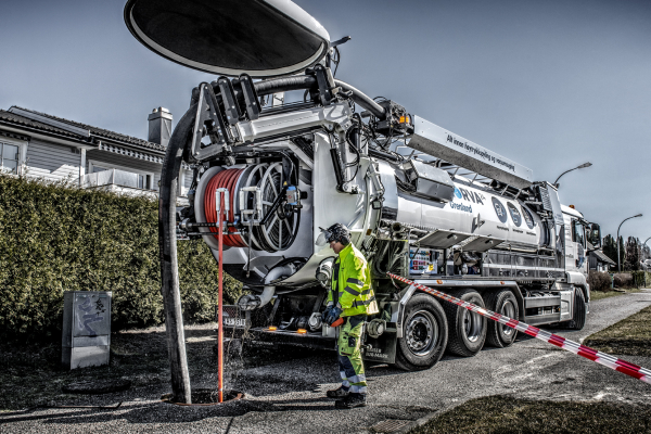Worker empties a sand trap using powerful vacuum equipment.