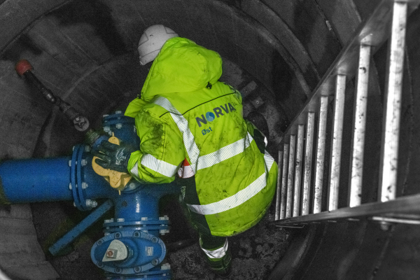 Worker inspecting a water supply system in an underground chamber.