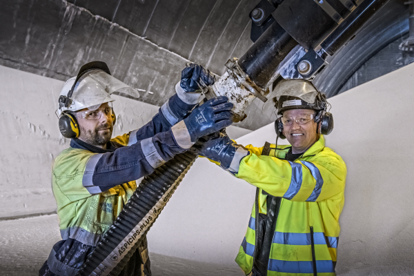Operators working together to connect industrial equipment.