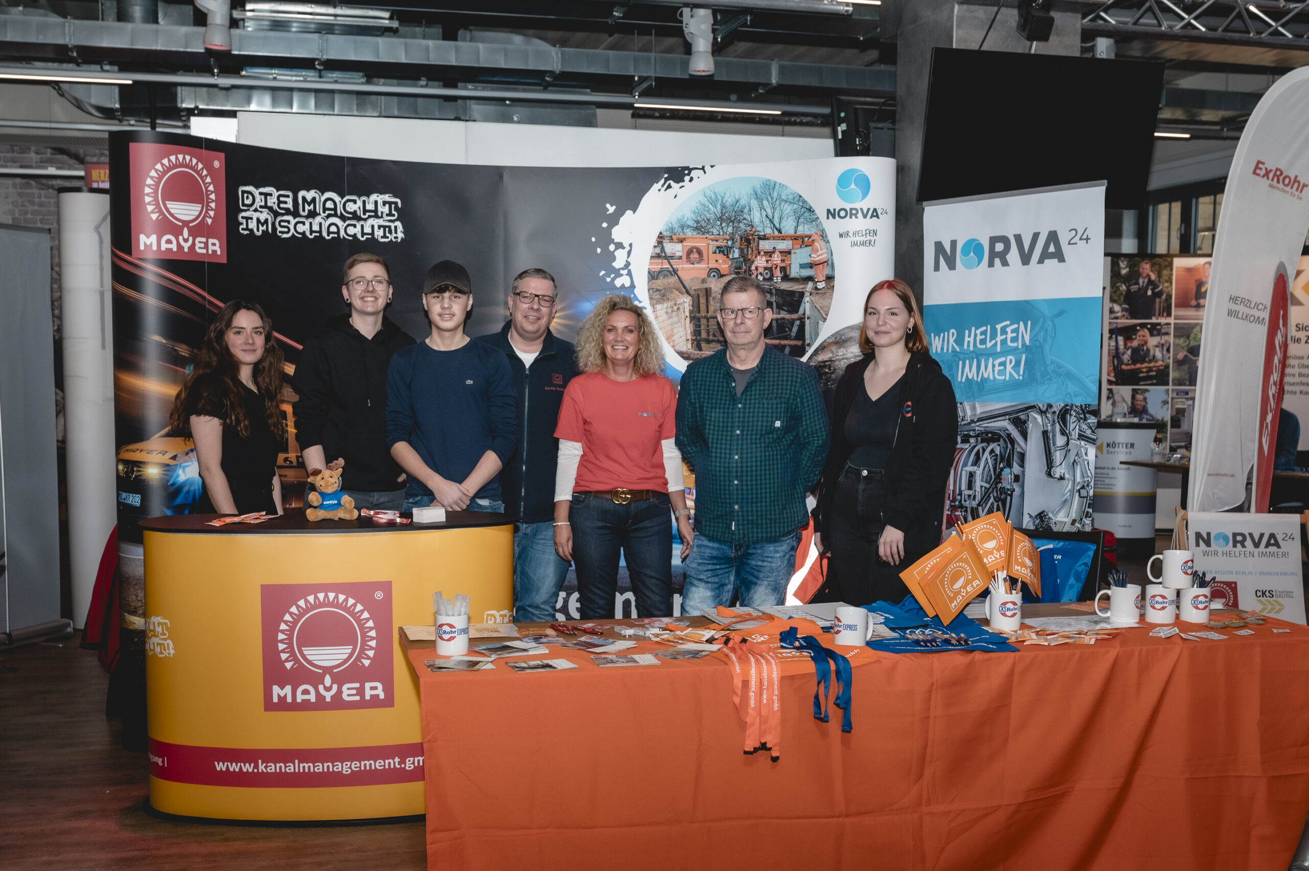 Group photo at an event, people standing by a booth.