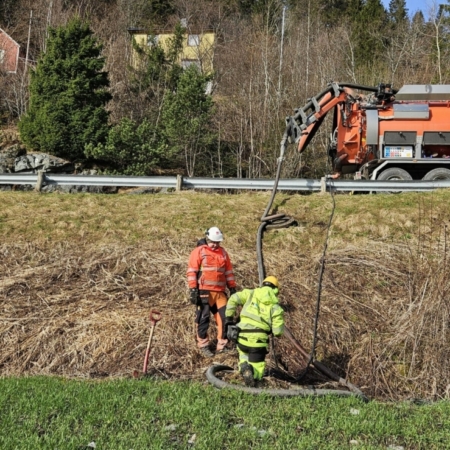Workers in safety gear doing drainage work with Norva24 truck on road above