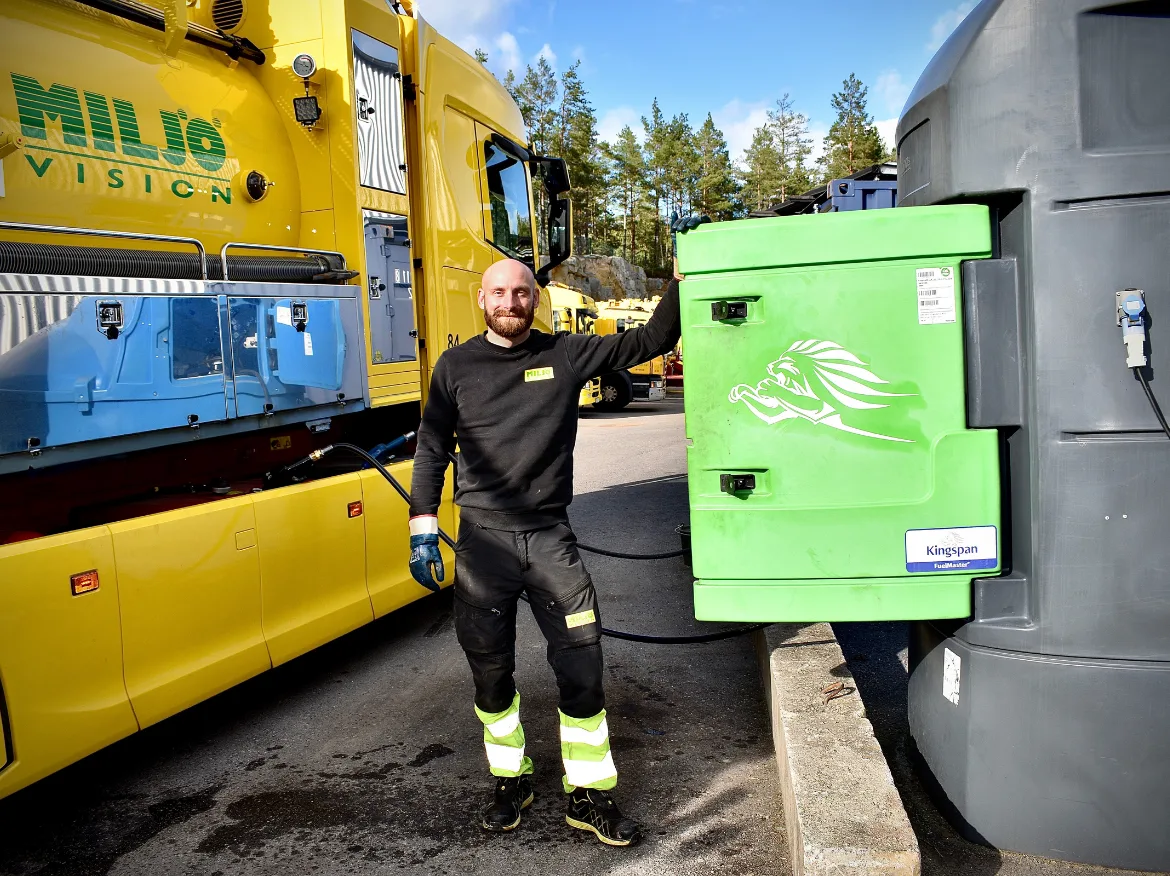 Man refueling yellow truck with HVO biofuel at depot