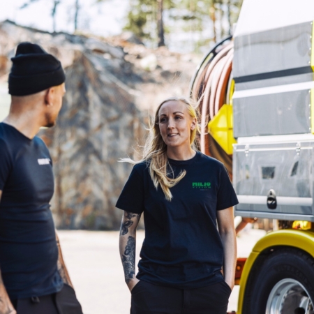 Two workers in black shirts talking next to a yellow truck outdoors