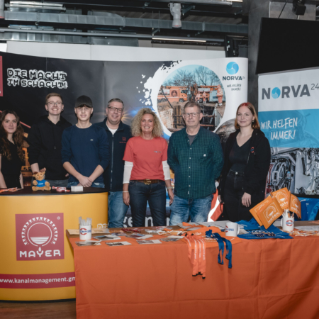 Group photo at an event, people standing by a booth.