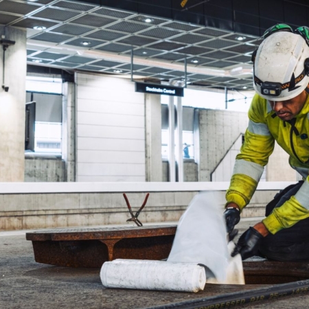 Worker in safety gear performing drain maintenance at Stockholm Central station