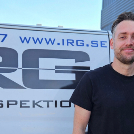 Smiling IRG employee in black company shirt standing in front of IRG service van